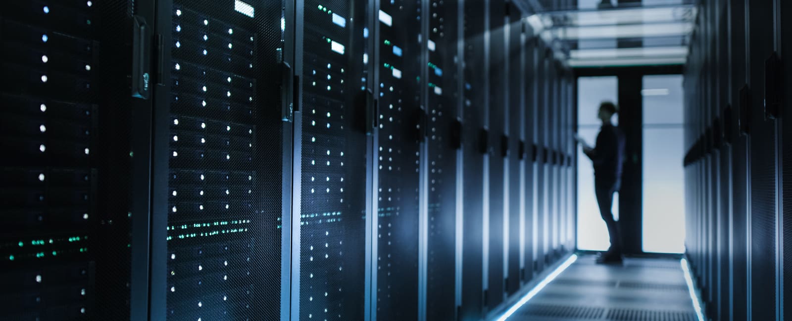 A person stands in the center of a server room.