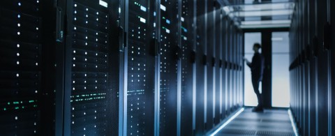 A person stands in the center of a server room.