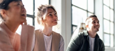 Three people sitting in an office, focused on something in front of them.