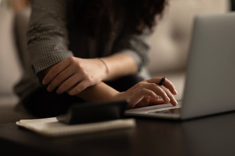 Closeup cropped image of a girl's hands typing on a laptop
