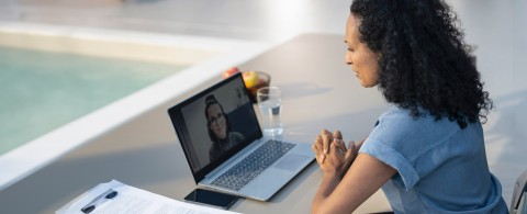 Woman watching a lecture on a laptop and taking notes